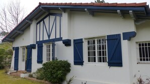 Een wit gebouw met blauwe luiken en een grote 'M' op de gevel.