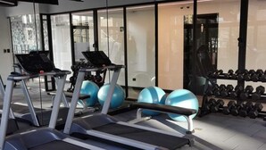 A gym with treadmills, exercise balls, and a rack of dumbbells.