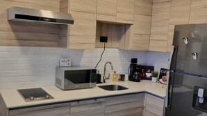 A modern kitchen with a microwave, sink, stove, and refrigerator.