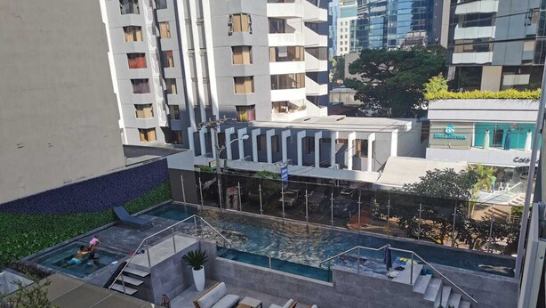 A rooftop pool area with lounge chairs and a small pool, surrounded by high-rise buildings.