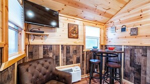 A cozy cabin interior with a television, a bar area, and a comfortable seating area. - Willow: Sleeps 3, Tiny Cabin, Pets, Near Lake/Park (Broken Bow)