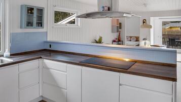A modern kitchen with white cabinetry, a blue-tiled backsplash, and a wooden countertop.