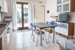 A modern kitchen with a dining area, a TV, and a sliding glass door leading to a patio.
