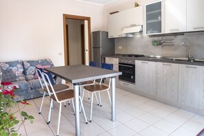 A compact kitchen with a dining table, chairs, a sofa, and a refrigerator. - S289 - Sirolo, delightful one bedroom apartment with porch (Sirolo)