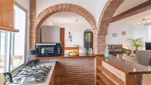 Una cocina con estufa a gas, microondas y un arco de ladrillo.
