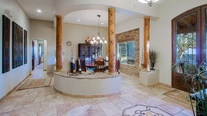 A spacious lobby with a central island, large wooden columns, a chandelier, and a stone wall. - Custom home with heated spa and pool, 1 acre, No HOA, bring Rvs (Phoenix)