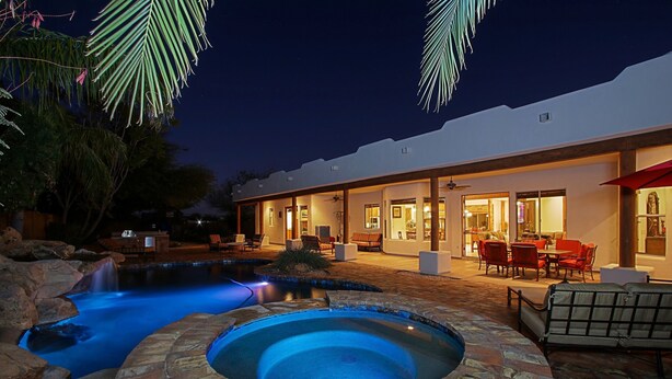 A well-lit outdoor pool area with a hot tub, surrounded by a patio with seating and a covered dining area. - Custom home with heated spa and pool, 1 acre, No HOA, bring Rvs (Phoenix)
