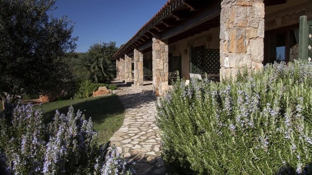 A stone building with a covered patio and a stone pathway leading to it. - Residenze di Campagna (Alghero)