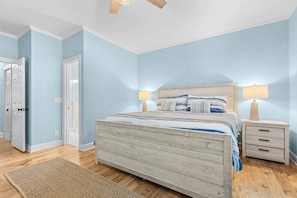 Une chambre à coucher avec un lit, des tables de chevet et un ventilateur de plafond.