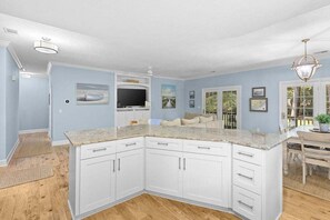 Cocina con gabinetes blancos, encimera de granito y televisor integrado.