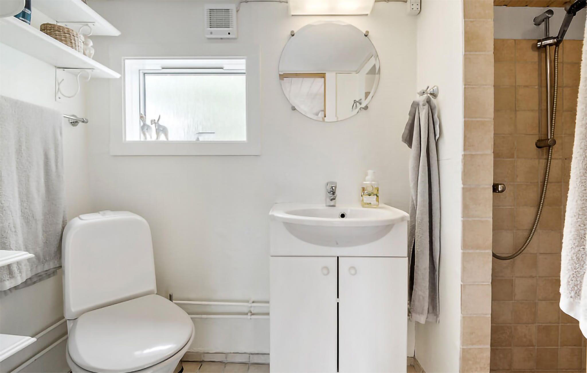 A bathroom with a toilet, sink, mirror, and shower.