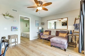 Un salon doté d’un ventilateur de plafond, d’un parquet, d’un canapé, d’une table basse et d’un miroir.