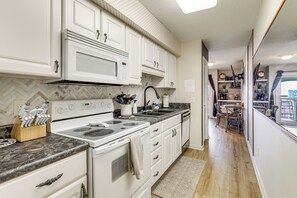 A kitchen with white cabinets, a stove, and a microwave. - Cozy Carolina Beach Condo w/ Ocean Views! (Carolina Beach)