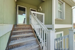 Un escalier en bois avec des rampes blanches menant à une porte verte.