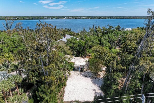 A secluded house surrounded by dense trees with a view of a large body of water.