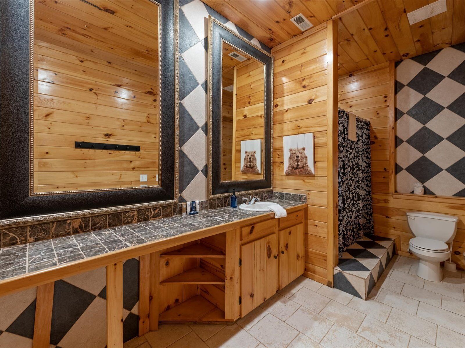 A wooden bathroom with a large mirror, a sink, and a toilet.
