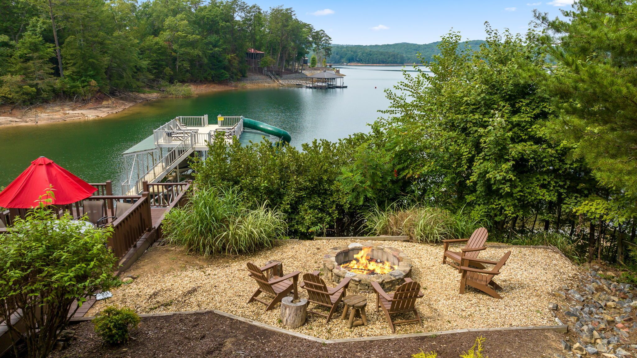 A lakeside deck with outdoor seating and a fire pit.