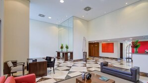 A spacious lobby with a checkered floor, a reception desk, seating areas, and a modern reception counter. - Etoile Hotels - George V - Itaim Bibi (São Paulo)