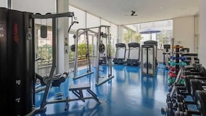 A gym with various exercise equipment, large windows, and a blue floor. - Etoile Hotels - George V - Itaim Bibi (São Paulo)