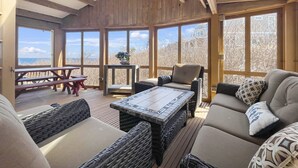 Une pièce spacieuse avec un plafond haut, des poutres en bois, de grandes fenêtres, une table à manger et des sièges confortables.