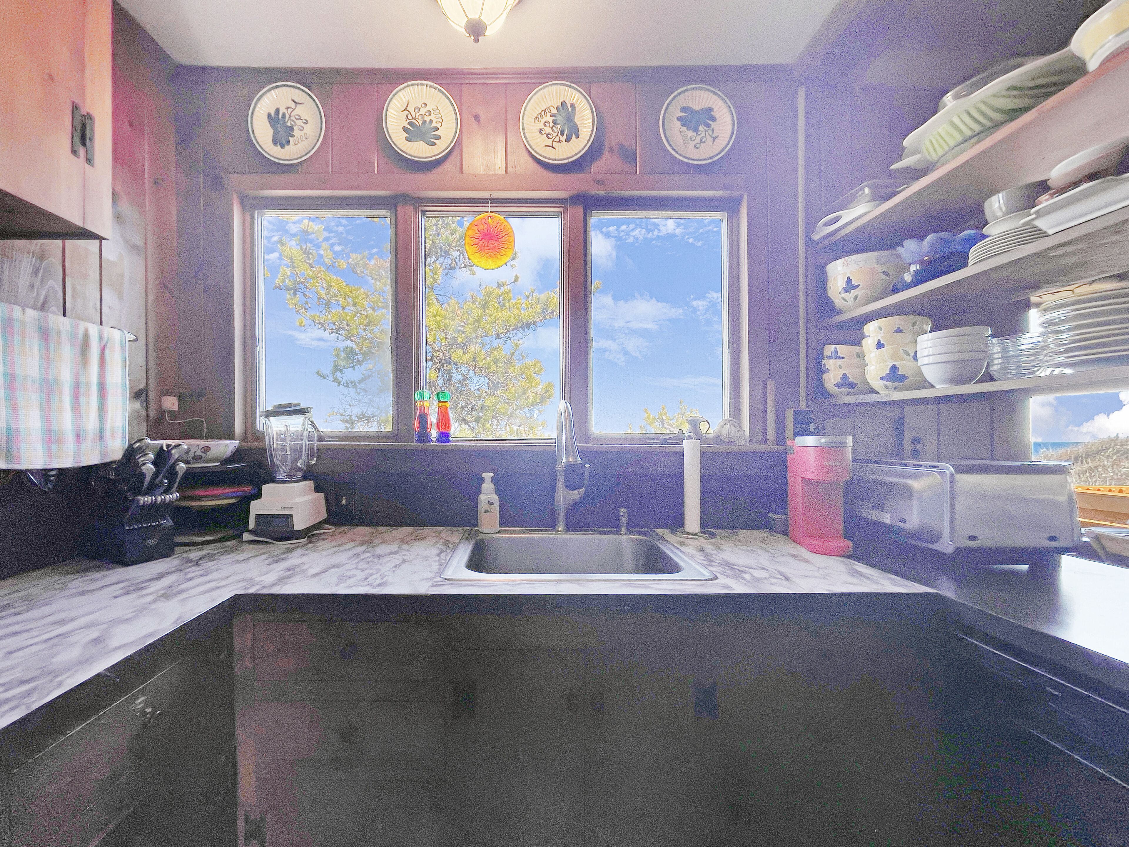 A kitchen with a large window, a sink, and various kitchen appliances.