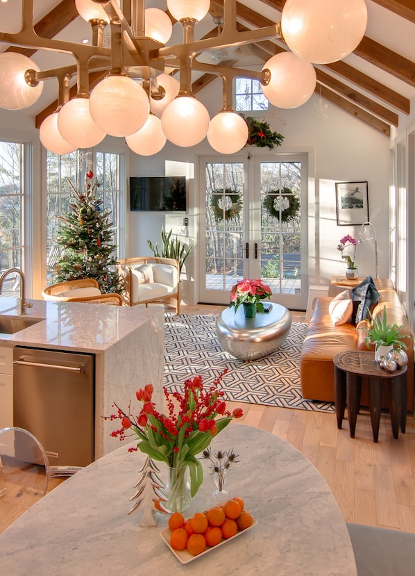 A modern kitchen with a marble countertop, a built-in dishwasher, and a dining area with a round table and chairs.