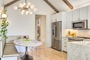 A modern kitchen with white cabinets, stainless steel appliances, and a marble island.