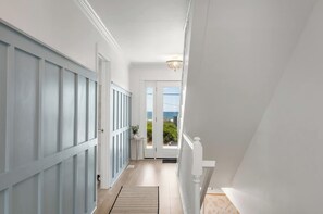 A hallway with a view to the outdoors, a door, and a small table with a plant.