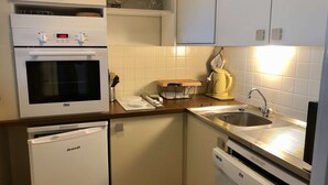 Una cocina compacta con horno integrado, cafetera y lavavajillas.