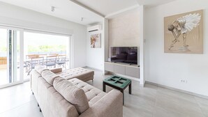 A modern living room with a sofa, a glass coffee table, a flat-screen TV, and artwork on the walls. - Lovely home in Primorski Dolac (Primorski Dolac)
