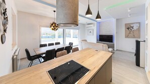 A modern kitchen with a central island, pendant lighting, and a dining area with chairs. - Lovely home in Primorski Dolac (Primorski Dolac)