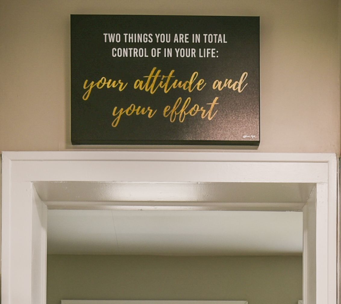A motivational quote plaque on a wall above a white door.