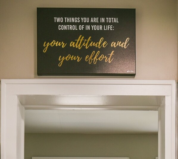 Uma placa com uma frase motivacional na parede acima de uma porta branca.