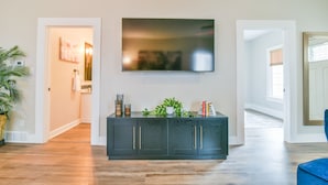 Een moderne woonkamer met een donker houten kast, een flatscreen televisie aan de muur en een plant in een pot op de kast.