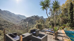 Zona de piscina con sillones de descanso y vistas a las montañas.
