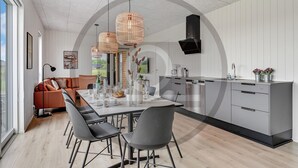 A modern kitchen with a dining area, featuring a large island, grey cabinetry, and pendant lighting. - 4 bedroom beautiful home in Løgstrup (Løgstrup)