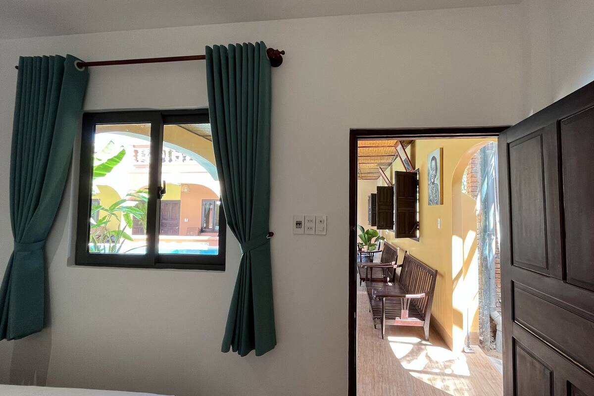 Quarto com janela, porta para uma varanda e vista exterior.