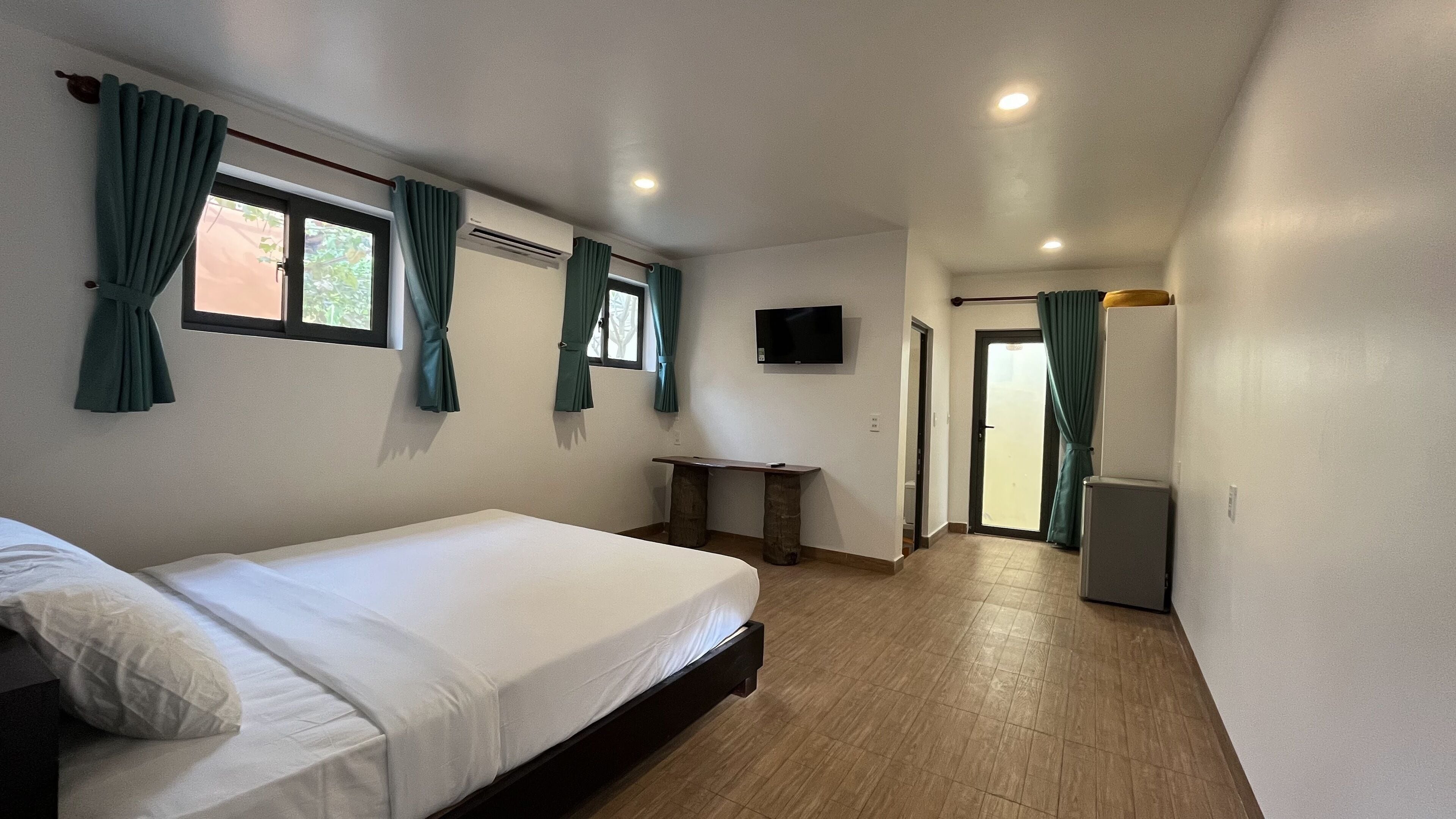A hotel room with a bed, a desk, a TV, and a sliding door.