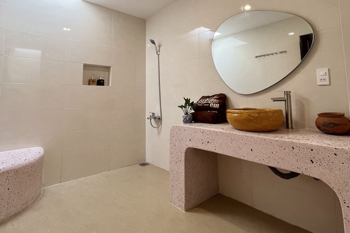Uma casa de banho moderna com uma banheira independente, um espelho grande e uma bancada com lavatório e objetos decorativos.