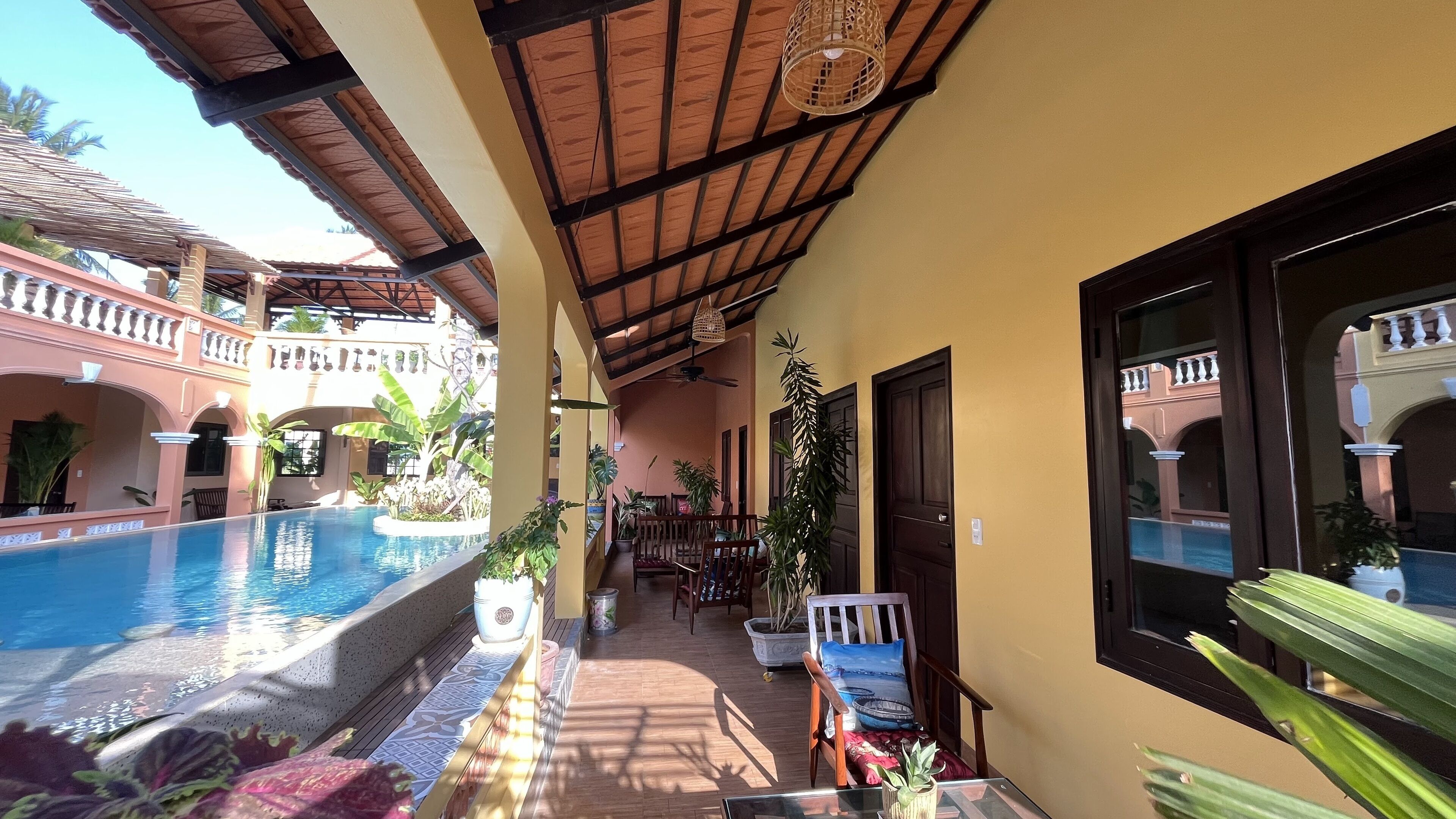 A pool area with a wooden deck, lounge chairs, and potted plants.