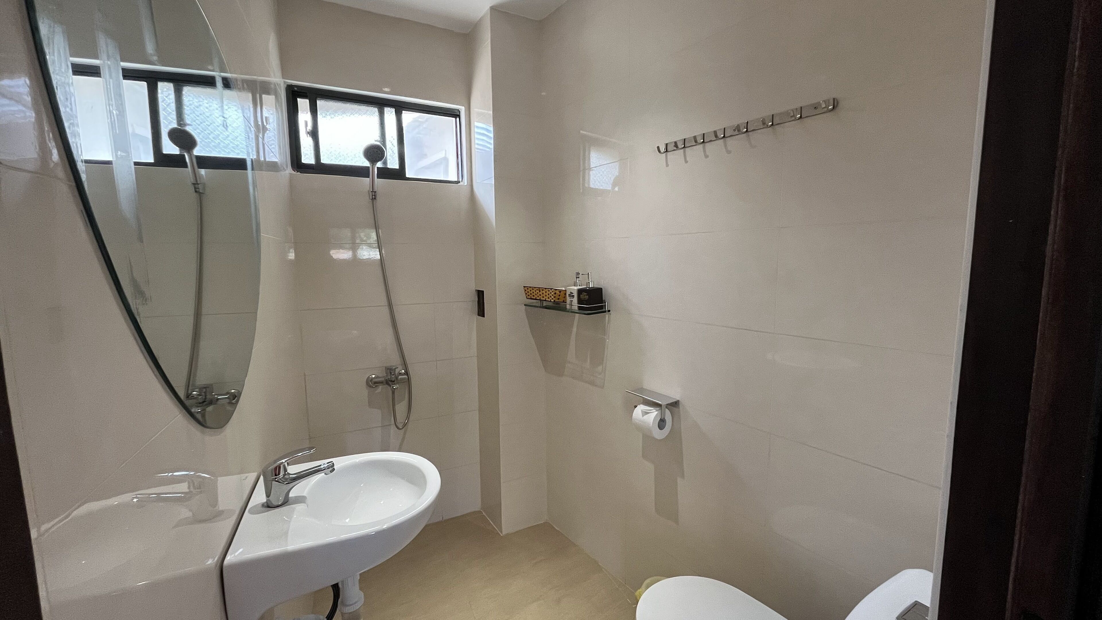 Ein modernes Badezimmer mit Waschbecken, Spiegel, Dusche und Toilette.