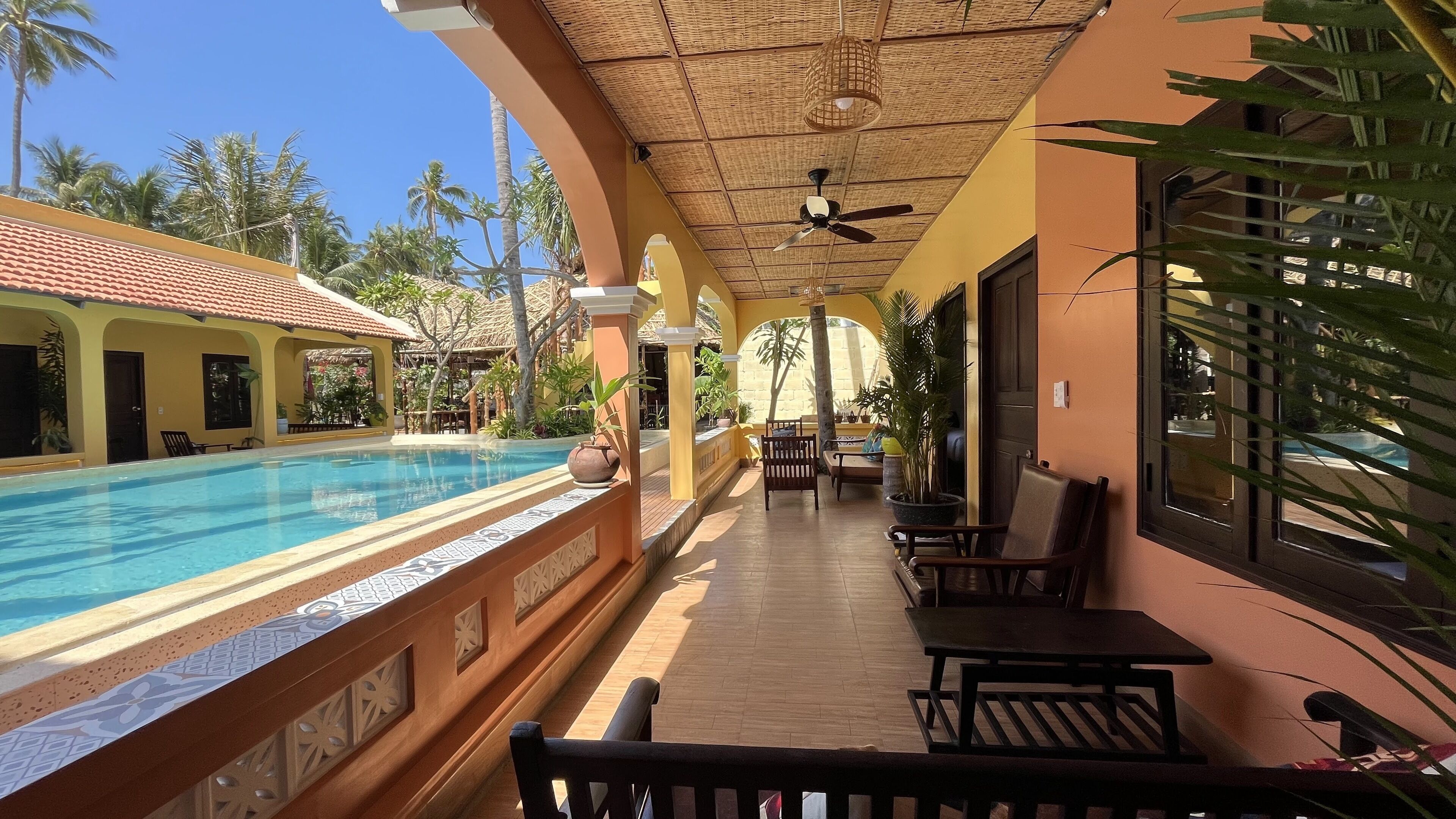 Zona junto a la piscina con vistas despejadas, ventilador de techo y mobiliario exterior.