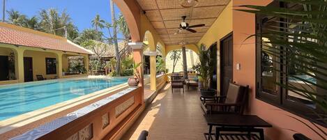Zona junto a la piscina con vistas despejadas, ventilador de techo y mobiliario exterior.