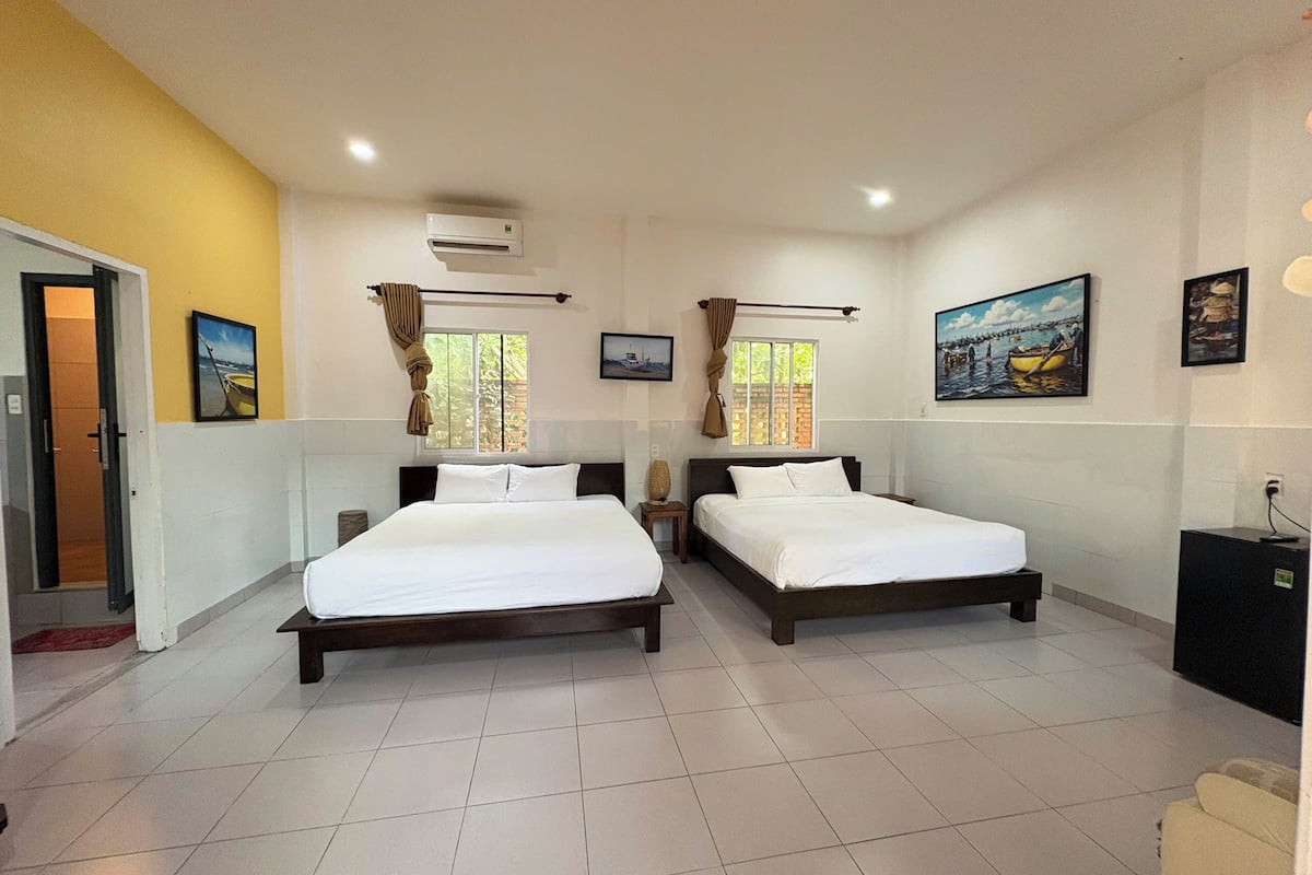 Quarto de hotel com duas camas, uma porta, uma janela e um quadro na parede.