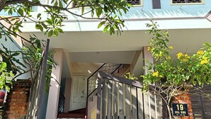 Una casa de dos pisos con un portón de madera, una escalera y un muro de ladrillo.