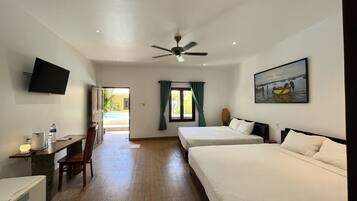 A hotel room with two beds, a desk with a chair, a television, and a ceiling fan.