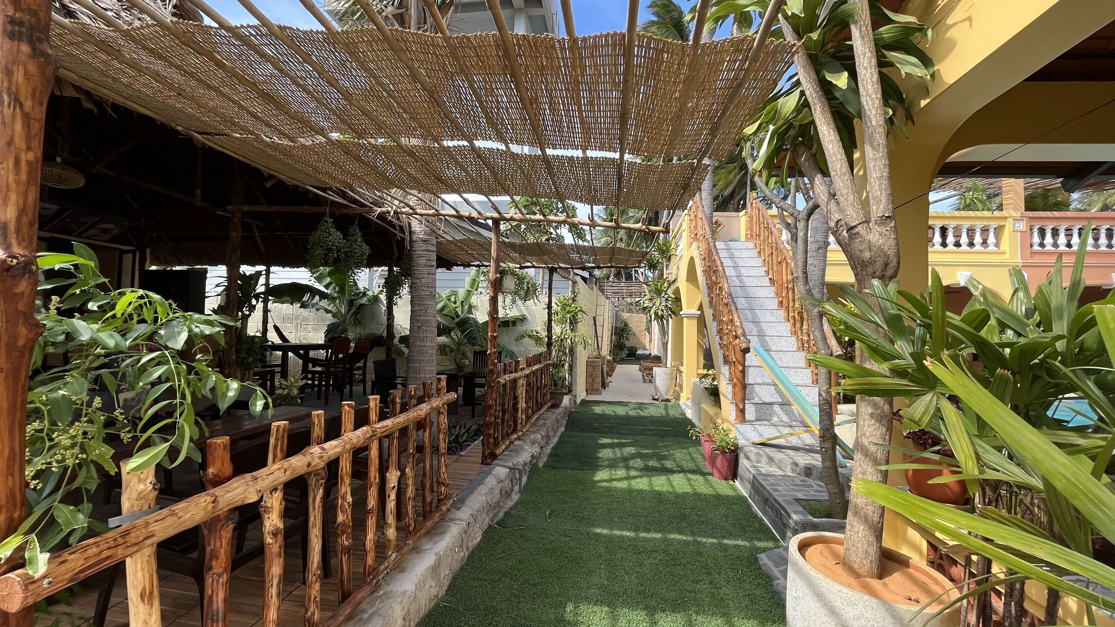 A covered outdoor area with a wooden fence, a small pathway, and potted plants.