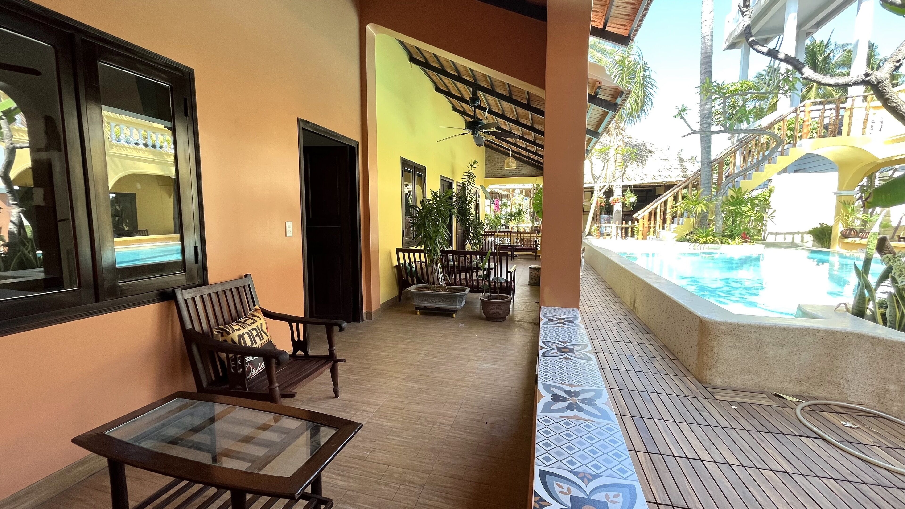 Un balcon d’hôtel avec une piscine, des meubles en bois et des plantes en pot.