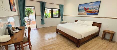 A hotel room with a bed, a desk with a chair, a small table, and a ceiling fan.