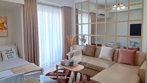 A modern living room with a sofa, a glass coffee table, and a large window with curtains. - Inspiria Condo Units beside Abreeza Mall Davao (Davao)